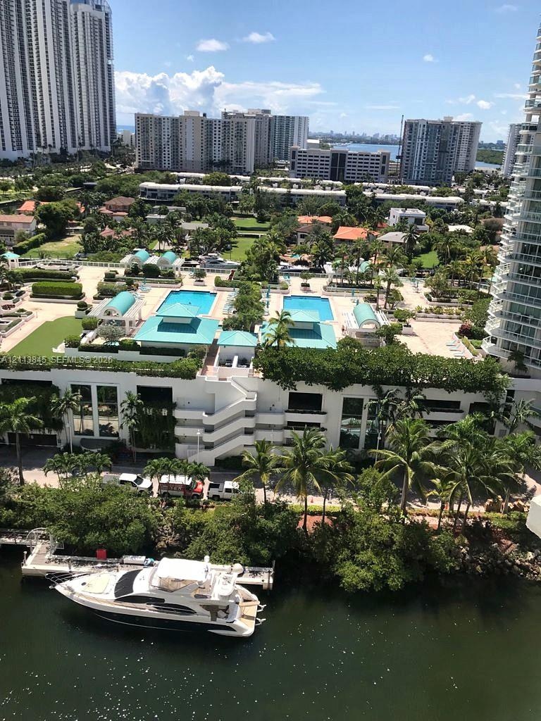 Aerial perspective featuring dual outdoor swimming pools, landscaped grounds, a boat dock, and waterfront access