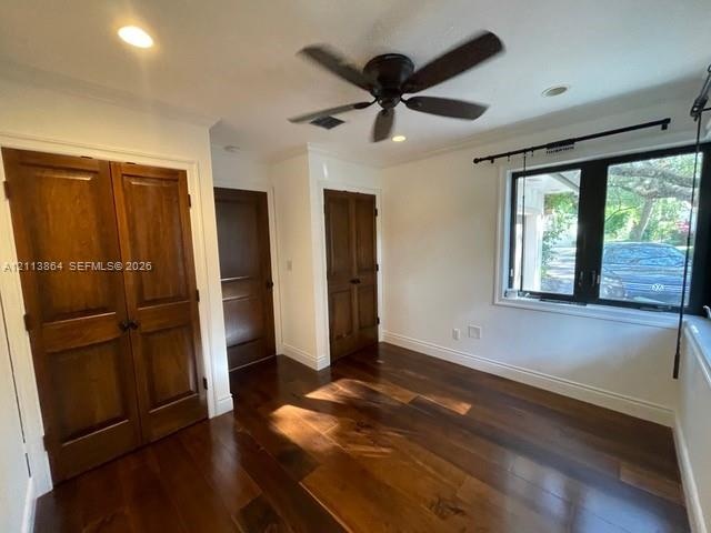 Interior space featuring wood-finish flooring, stained wood double-door closet cabinetry, a multi-pane window with a black frame, and a ceiling-mounte