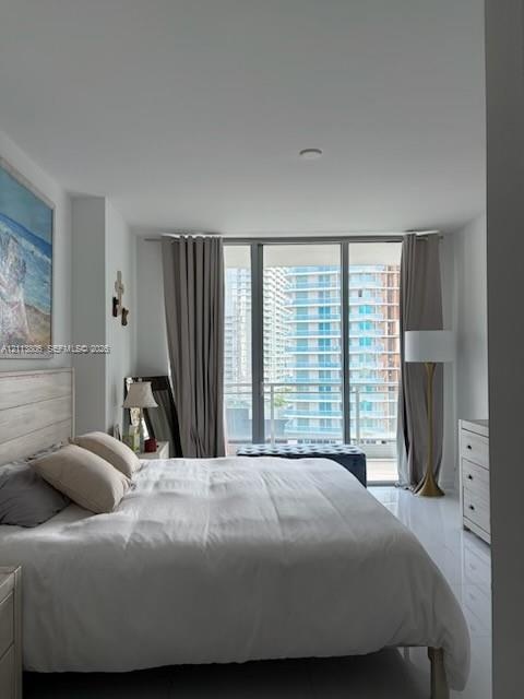 Floor-to-ceiling windows featuring access to a private balcony, polished tile flooring, and neutral wall finishes