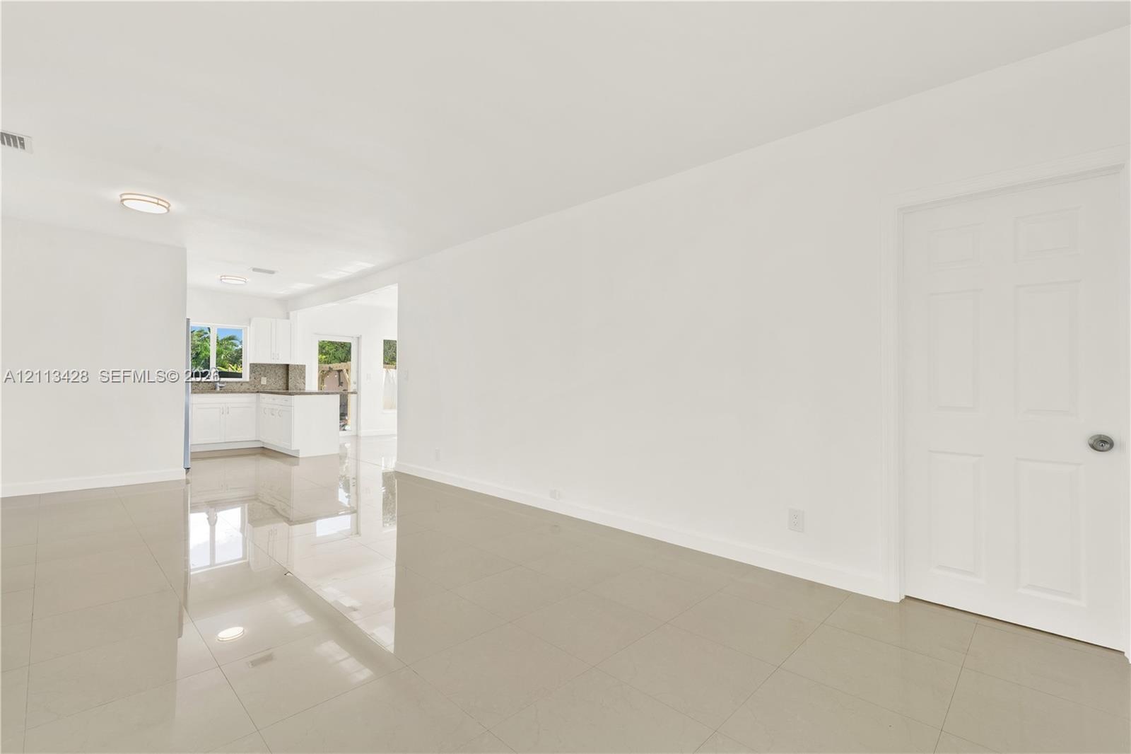 Interior featuring light-toned large-format tile flooring, six-panel interior door, and recessed lighting