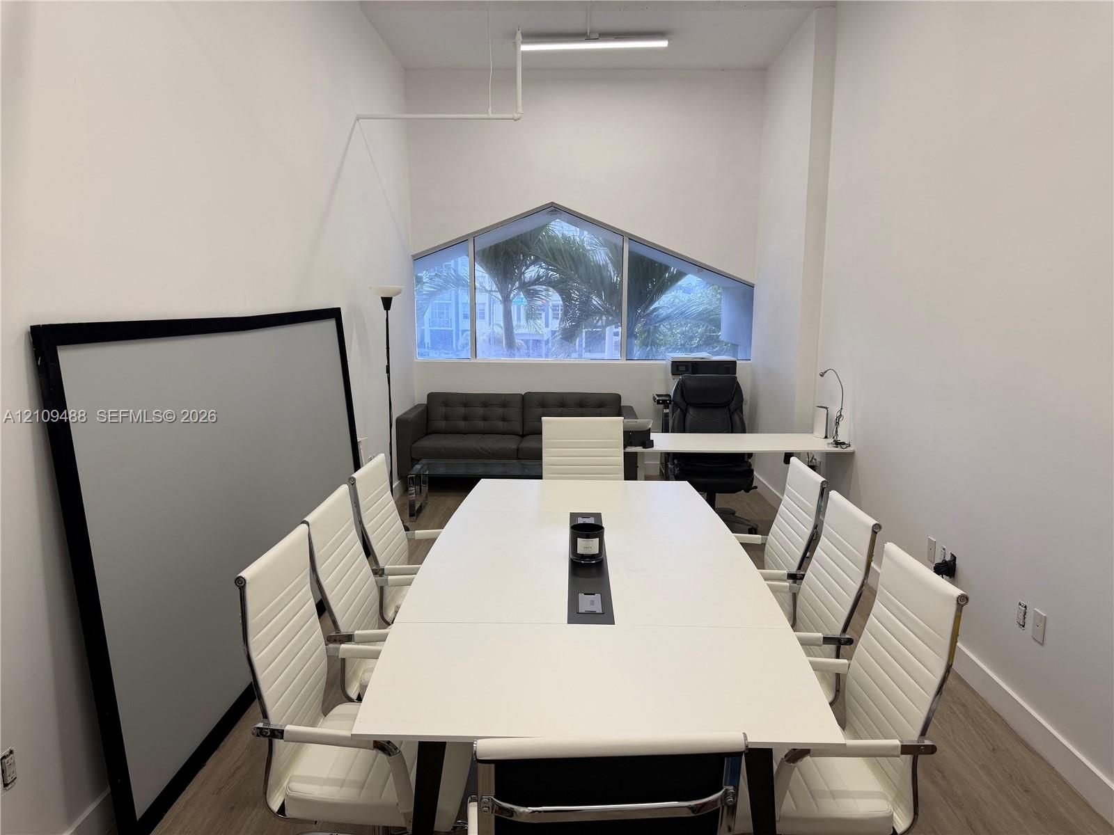 High-ceilinged room featuring wood-finish flooring and a geometric-shaped window
