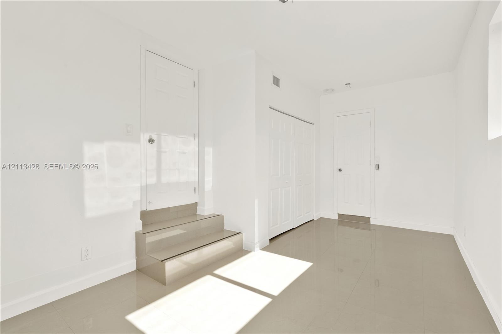Neutral-toned polished tile flooring, multi-panel interior doors, and built-in closet storage