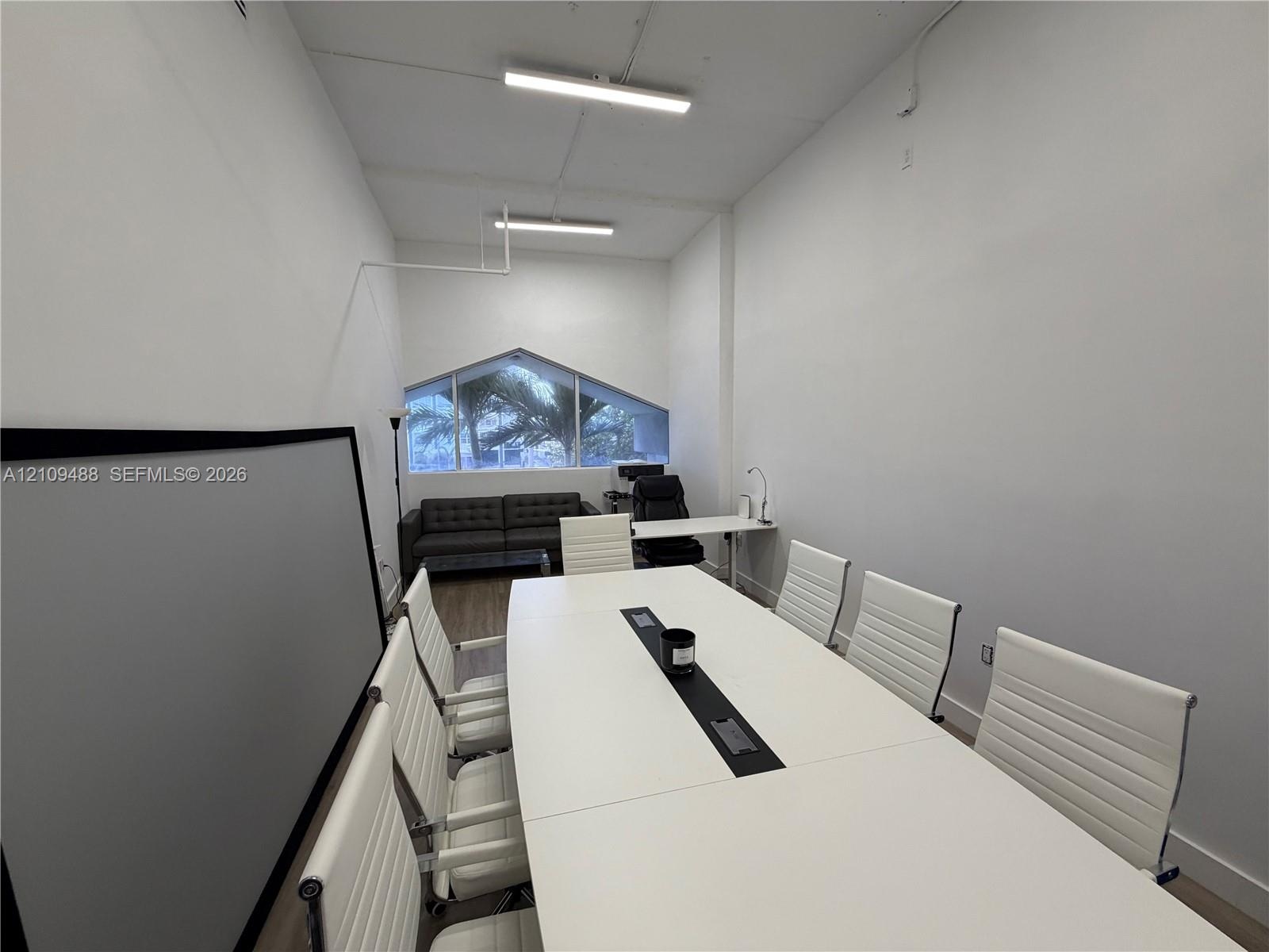 High-ceiling interior featuring wood-finish flooring, linear LED lighting, and a prominent angular-shaped window