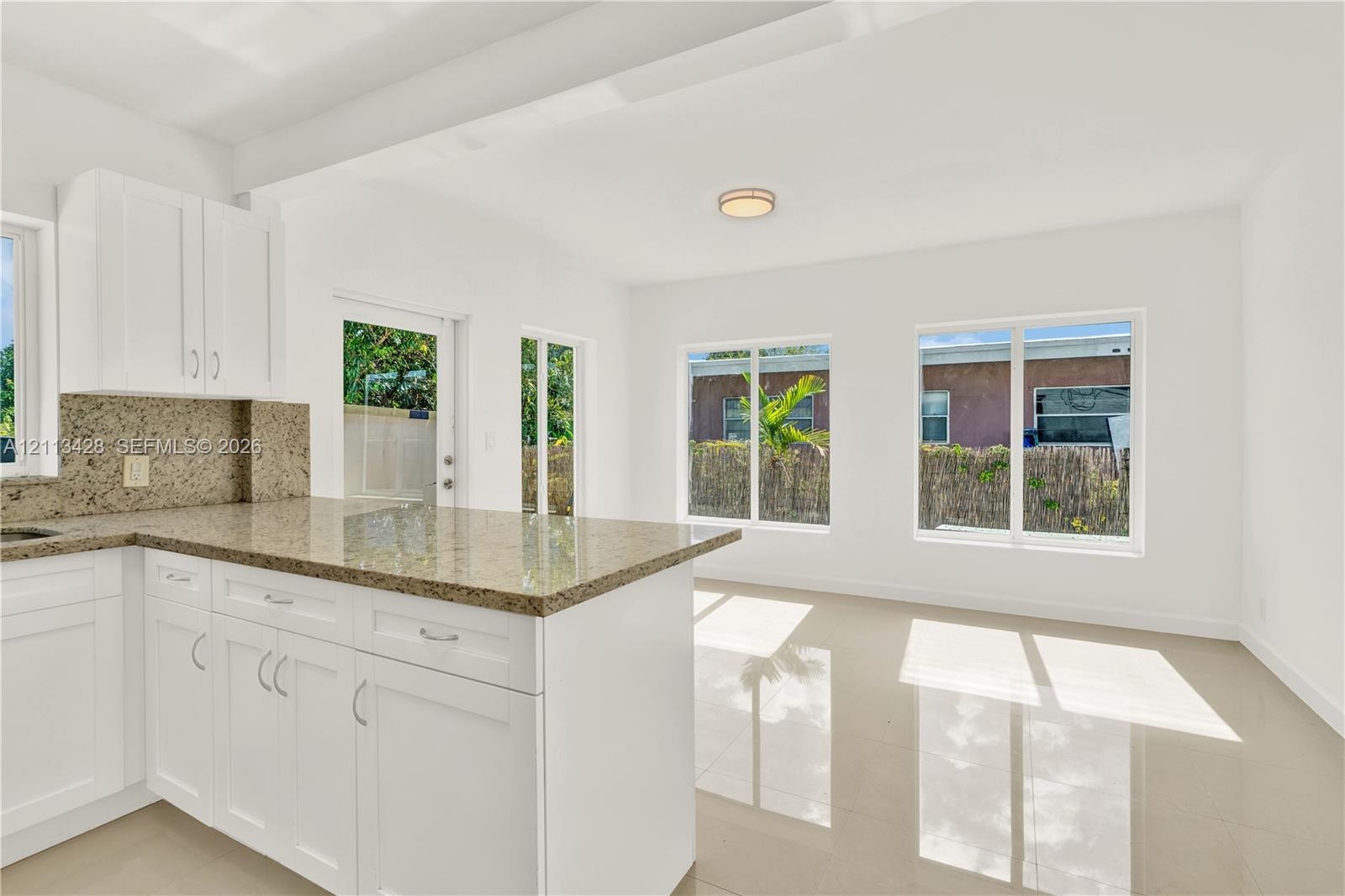 White cabinetry featuring a central island, stone-finish countertops, tile flooring, and large windows