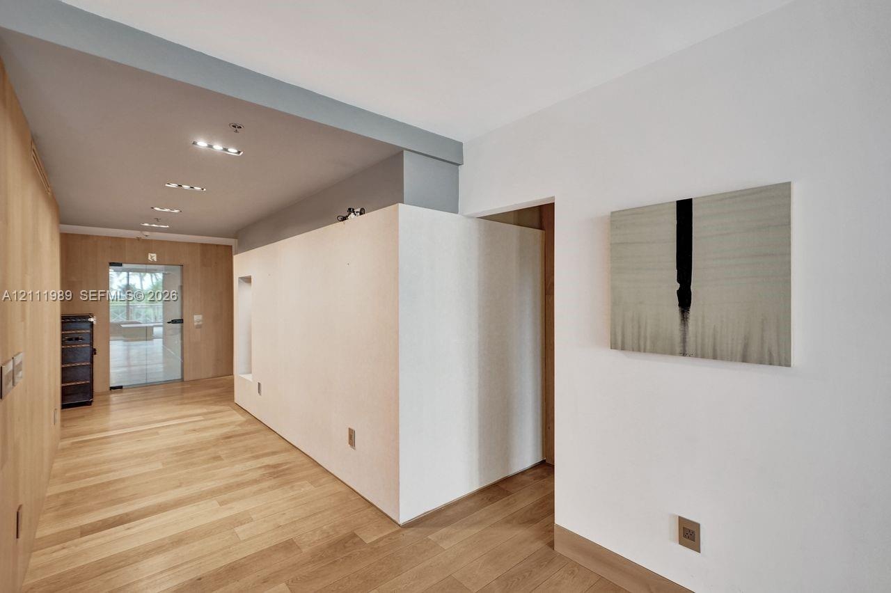 Interior space featuring wood-finish flooring, custom wood-panel wall treatments, recessed ceiling lighting, and a glass-paneled entry door