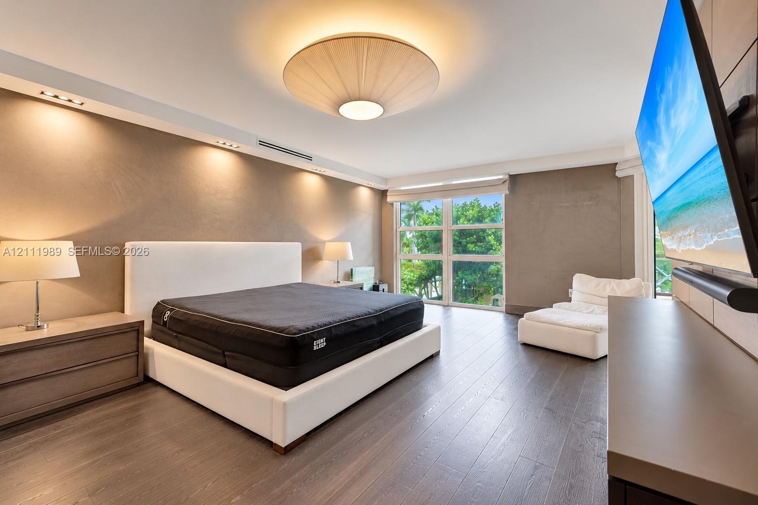Wood-finish flooring, recessed ceiling lighting, textured wall finishes, large grid-paned window, and a circular drum pendant light fixture