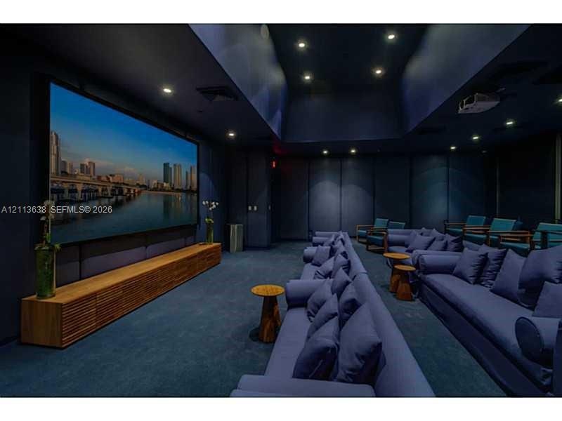 Dedicated media room featuring a large-format projection screen, recessed ceiling lighting, wall-integrated acoustic paneling, and a custom built-in w