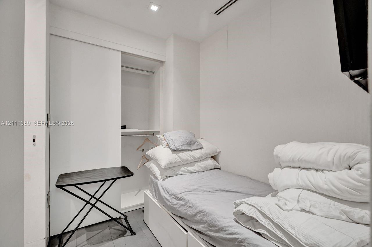 Built-in storage closet with sliding doors, recessed ceiling lighting, and hard-surface flooring