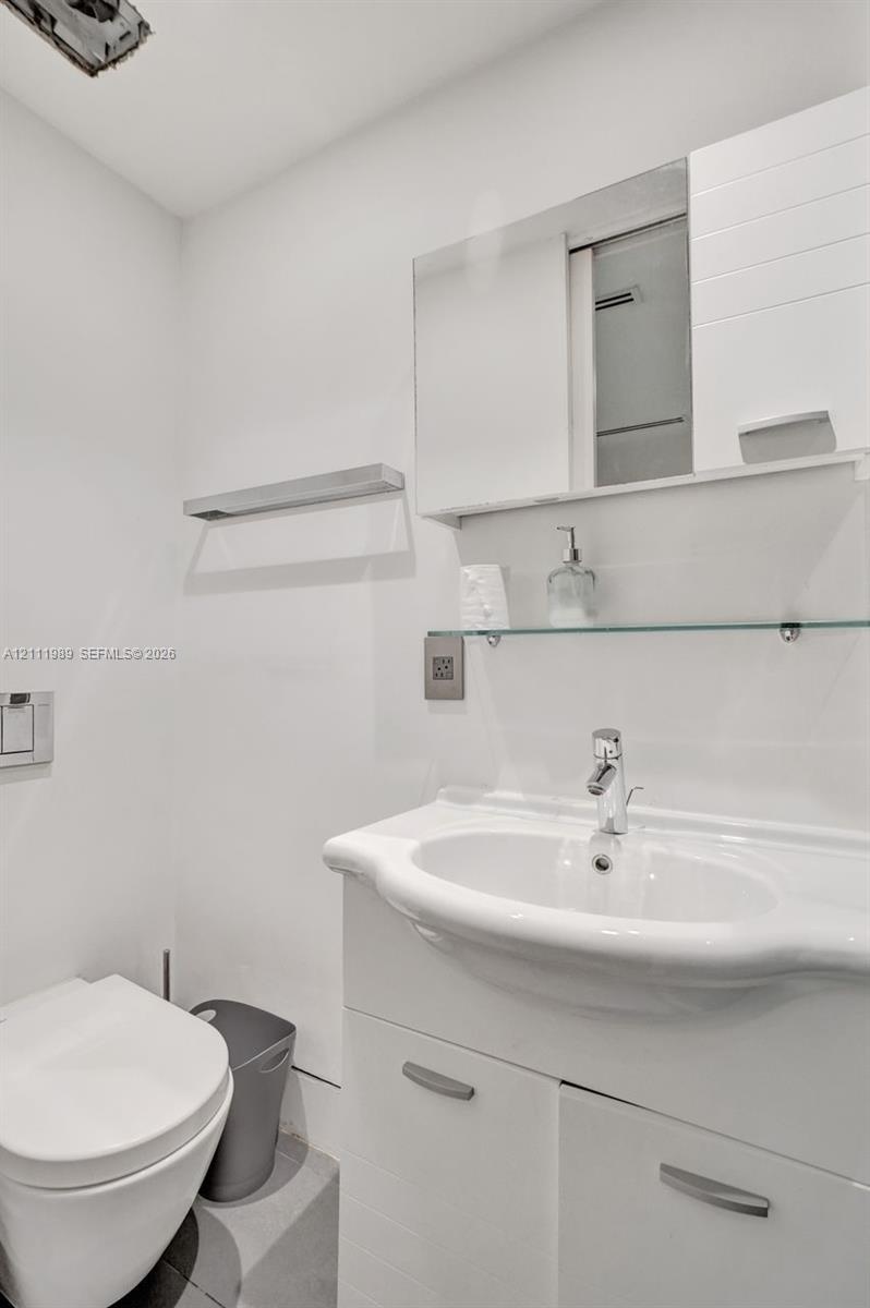Vanity featuring a white ceramic integrated sink, chrome faucet, and built-in lower cabinetry with brushed metal hardware