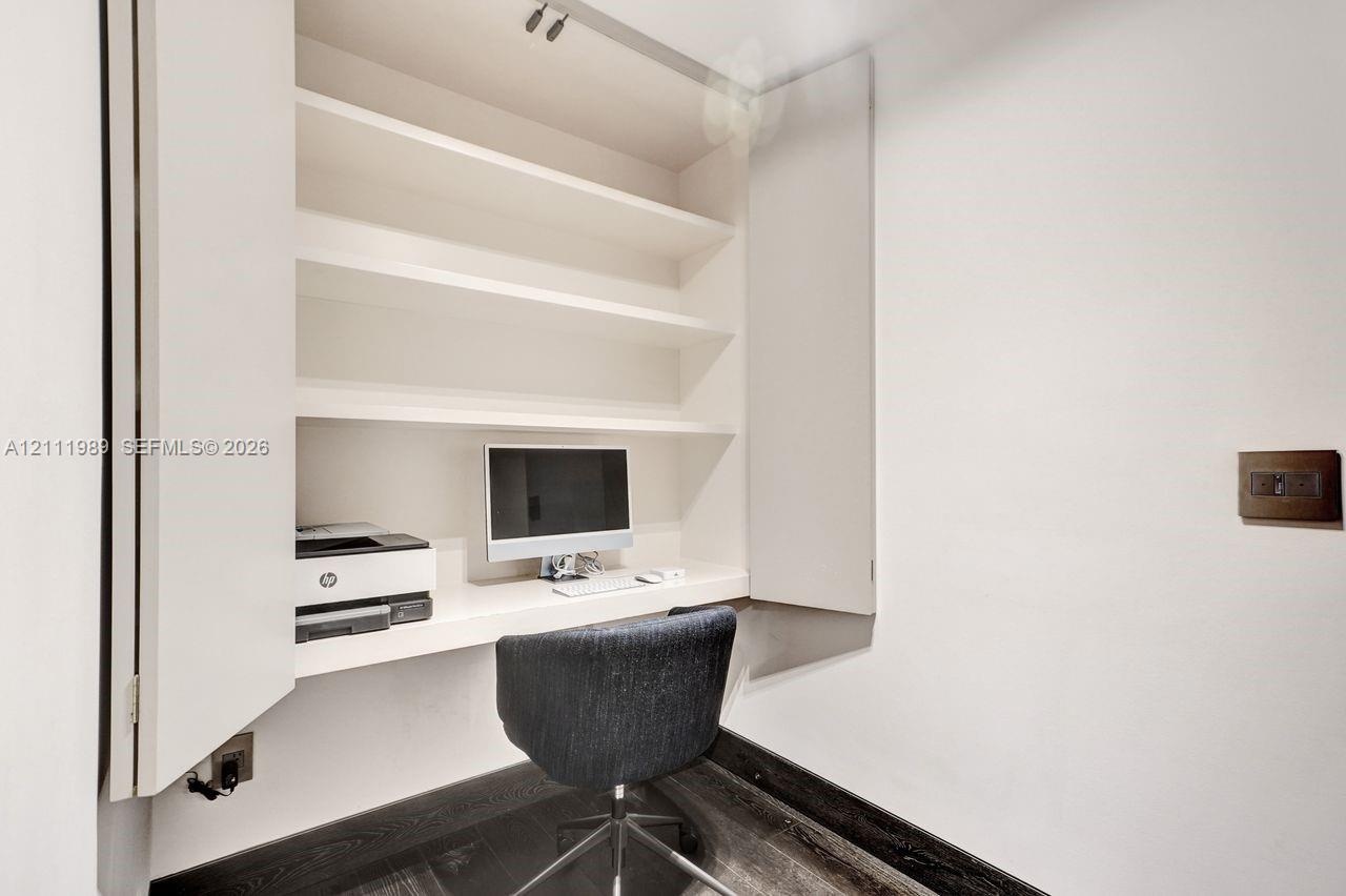 Built-in cabinetry featuring recessed shelving and a integrated desk surface, paired with wood-finish flooring