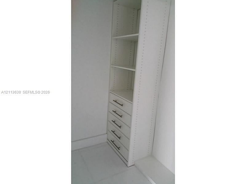 Built-in cabinetry featuring white shelving, five drawers, and metallic hardware
