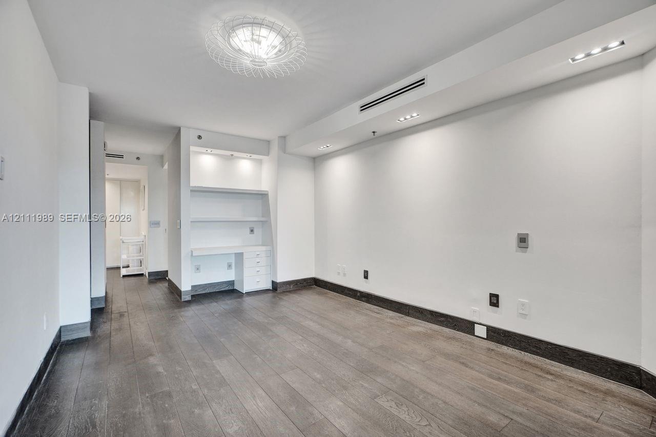 Wood-finish flooring, built-in cabinetry with integrated desk space, recessed ceiling lighting, and a decorative modern chandelier