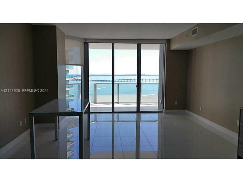 Floor-to-ceiling sliding glass doors, polished tile flooring, and private balcony with railing