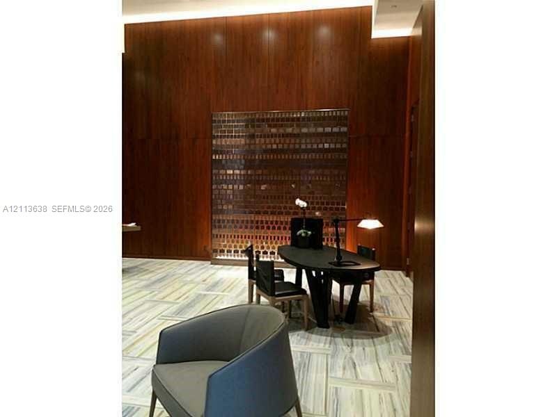 Full-height wood paneling featuring a floor-to-ceiling illuminated metal feature wall and polished stone flooring