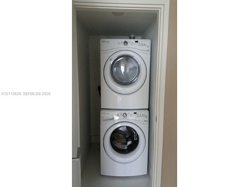 Stacked laundry unit featuring white front-loading machines housed within a recessed closet space