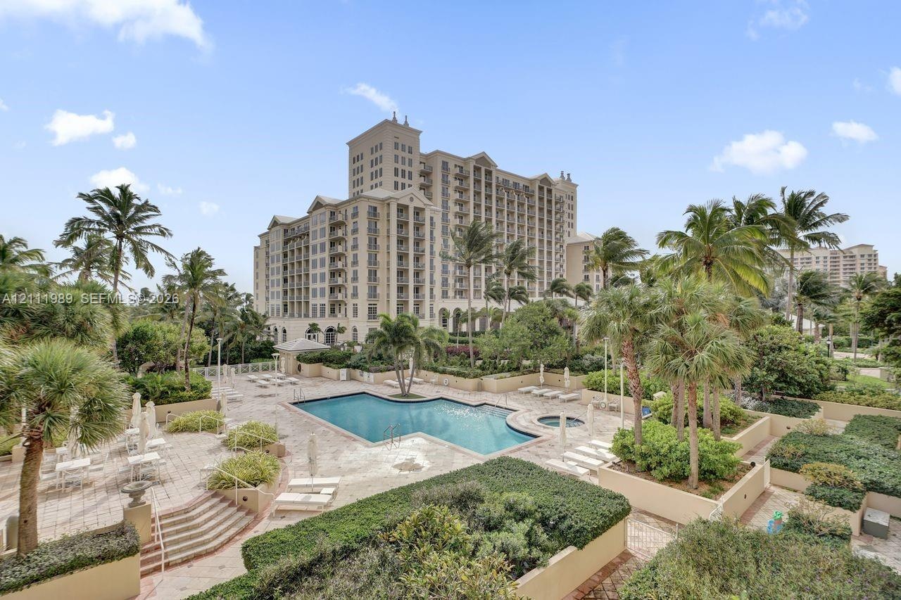 Resort-style pool area featuring a multi-level stone deck, integrated spa, and manicured tropical landscaping