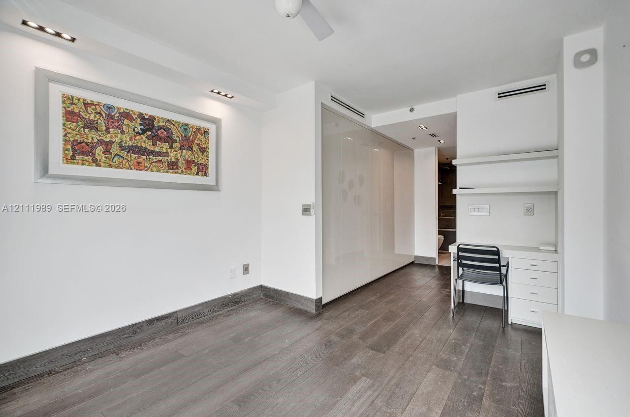 Wood-finish flooring, high-gloss built-in floor-to-ceiling cabinetry, recessed lighting, and a built-in workstation with integrated shelving and drawe