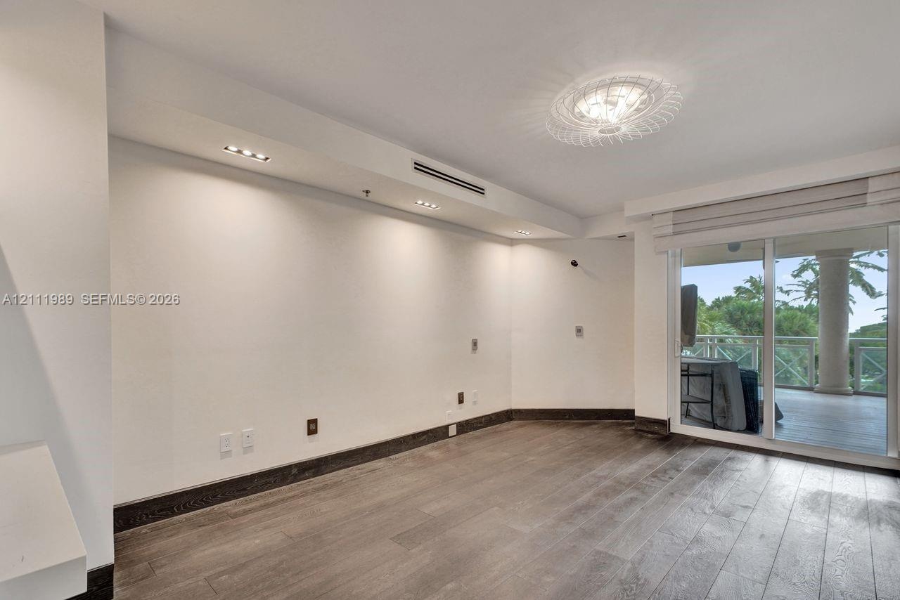 Interior space featuring wood-finish flooring, recessed ceiling lighting, a decorative flush-mount light fixture, and sliding glass doors with direct 