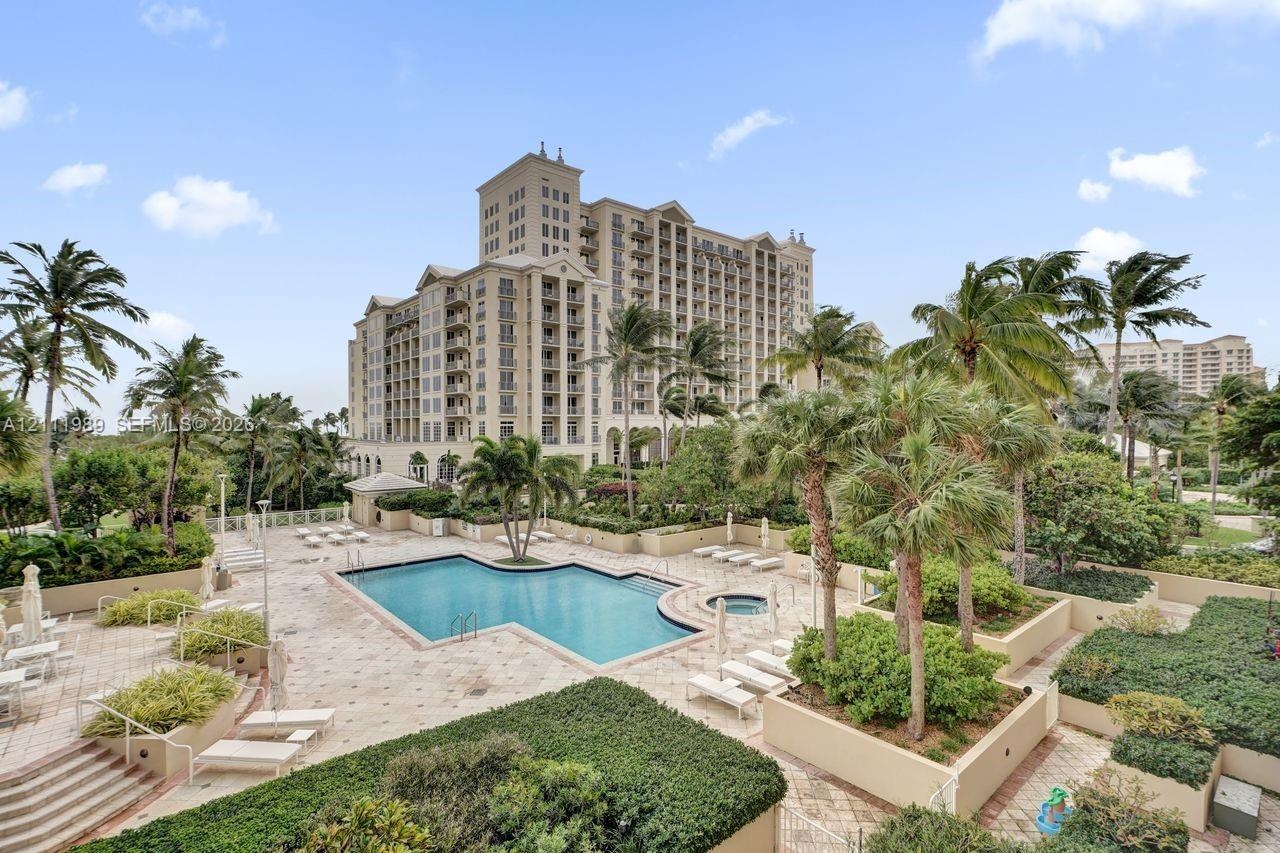High-rise residential complex featuring a swimming pool, an attached hot tub, paved sun deck, and tropical landscaping