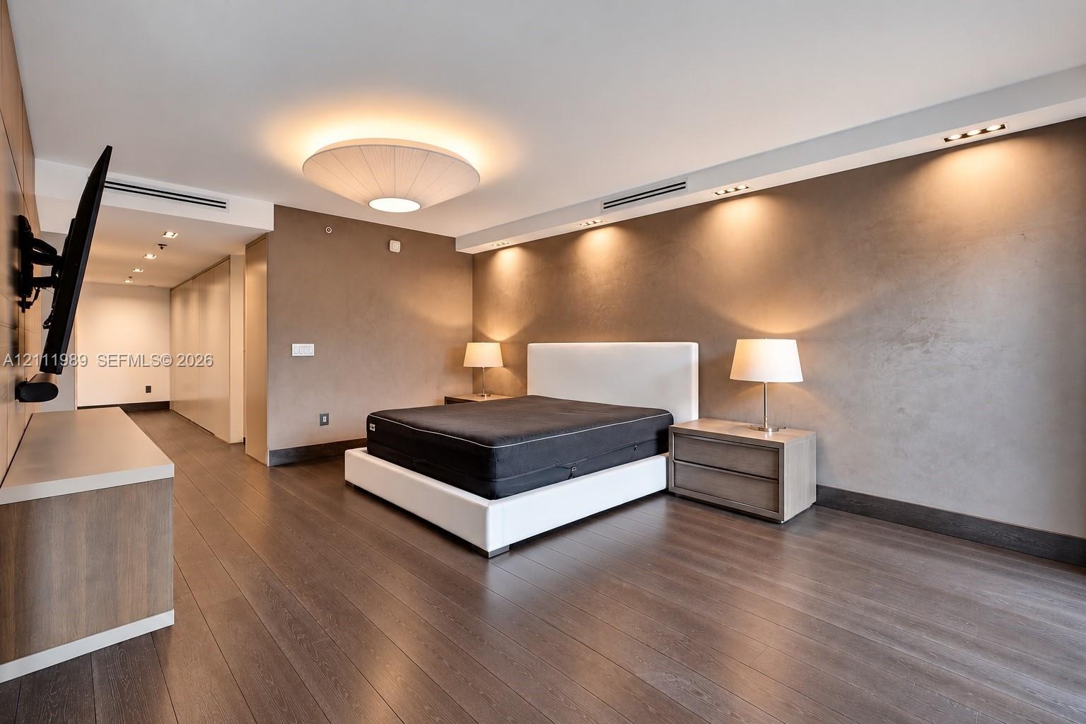 Wood-finish flooring, recessed ceiling lighting, textured wall finish, integrated linear HVAC diffusers, and a low-profile circular overhead fixture