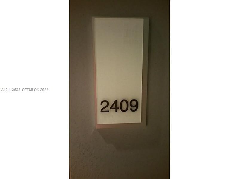 Wall-mounted unit identifier featuring a rectangular opaque panel with contrast lettering