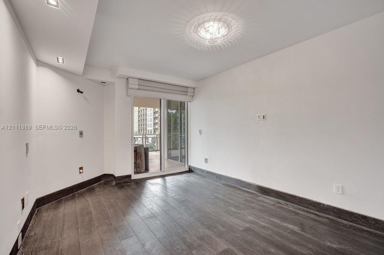 Room featuring wood-finish flooring, recessed lighting, a modern ceiling fixture, and a sliding glass door providing external access