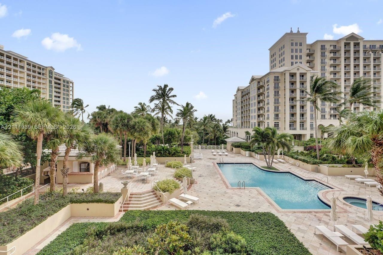 Resort-style community grounds featuring a swimming pool, integrated spa, tiled sundeck, and palm-lined landscaping