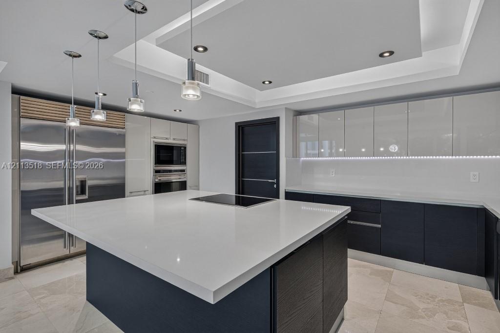 Contemporary kitchen featuring a spacious center island with a stone countertop, high-gloss cabinetry, stainless steel professional-grade appliances, 