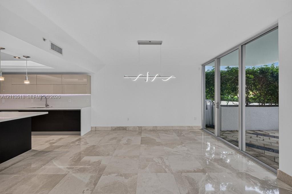 Open-concept interior featuring large-format tile flooring, high-gloss cabinetry, a quartz waterfall island, modern linear architectural lighting, and