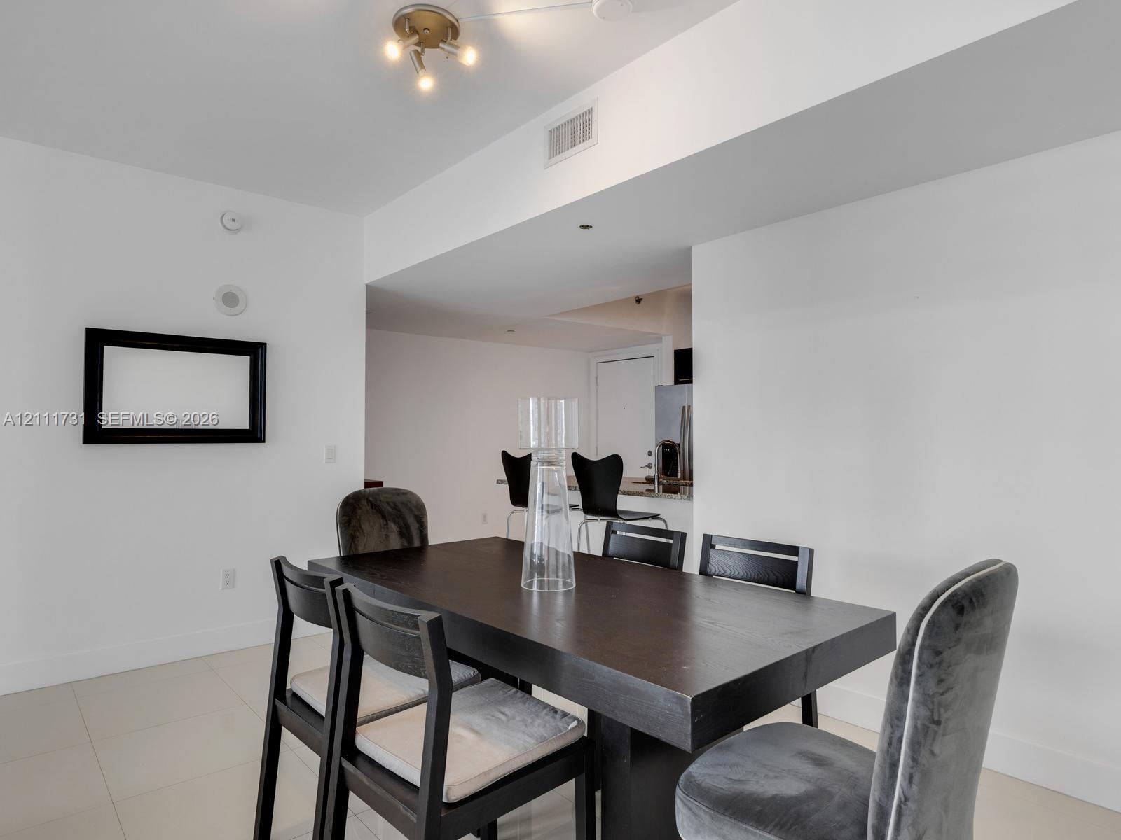 Neutral-toned tile flooring, recessed architectural soffit, and multi-light ceiling fixture