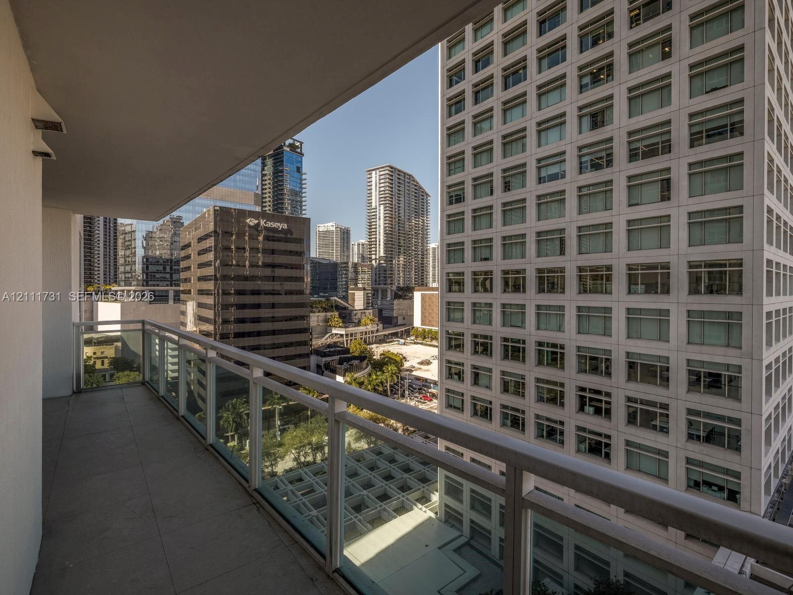 Covered balcony featuring concrete flooring and a transparent glass panel railing with metallic frame accents