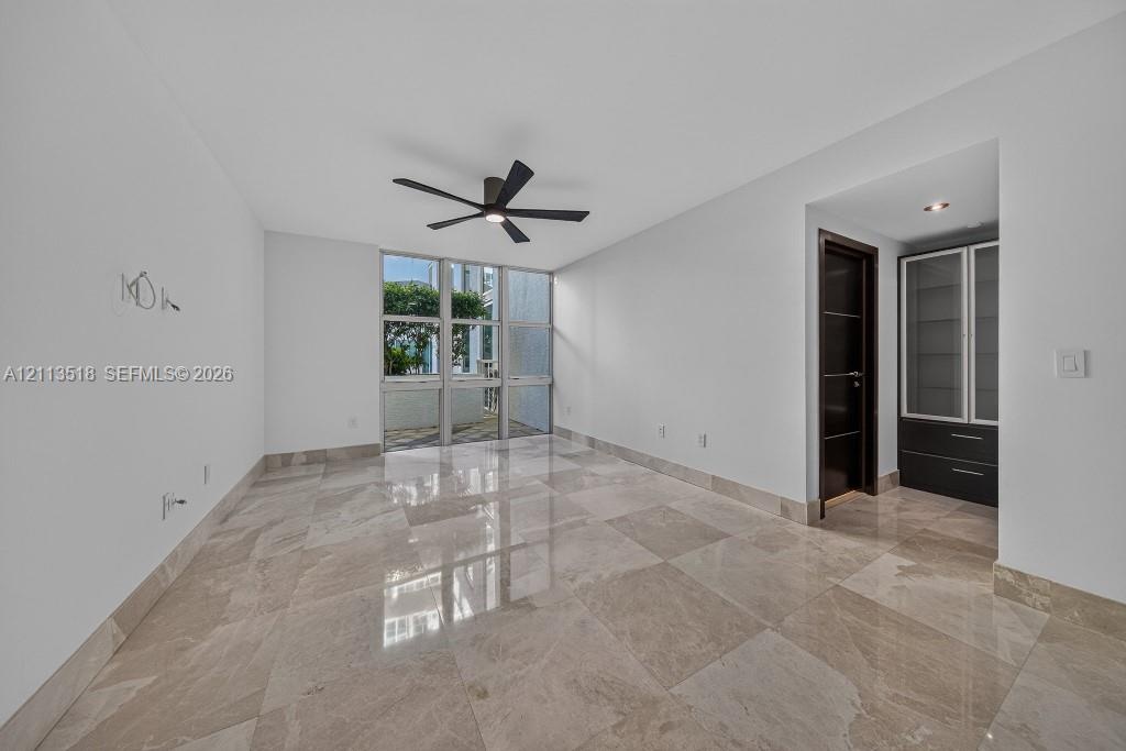 Polished stone flooring, floor-to-ceiling windows, dark wood-finish interior doors, recessed ceiling lighting, and built-in cabinetry with glass-front
