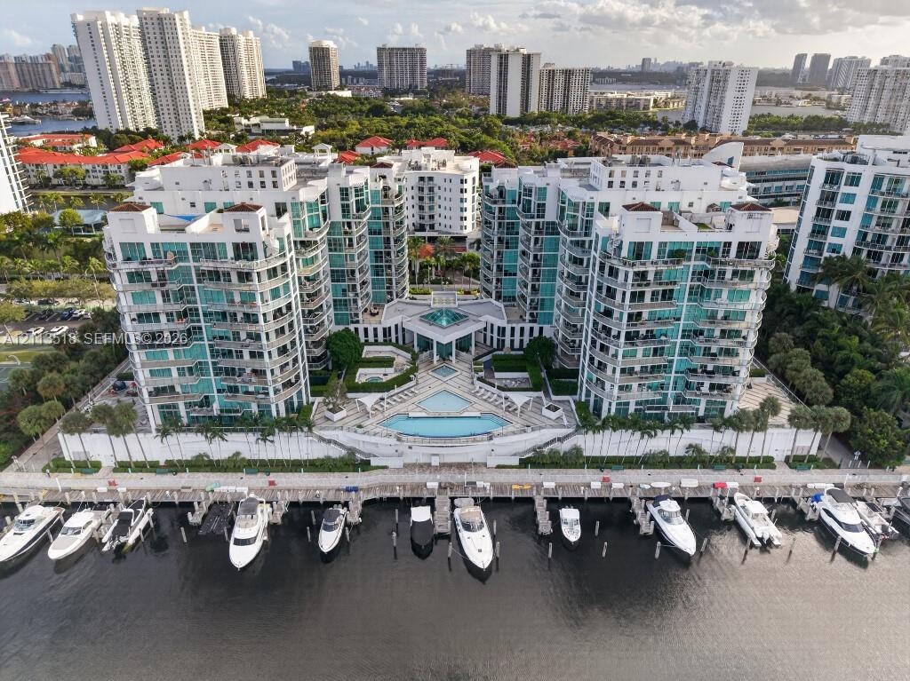 Multi-story residential complex featuring private deep-water boat slips, expansive waterfront sun deck, tiered swimming pool, and glass-railed balconi