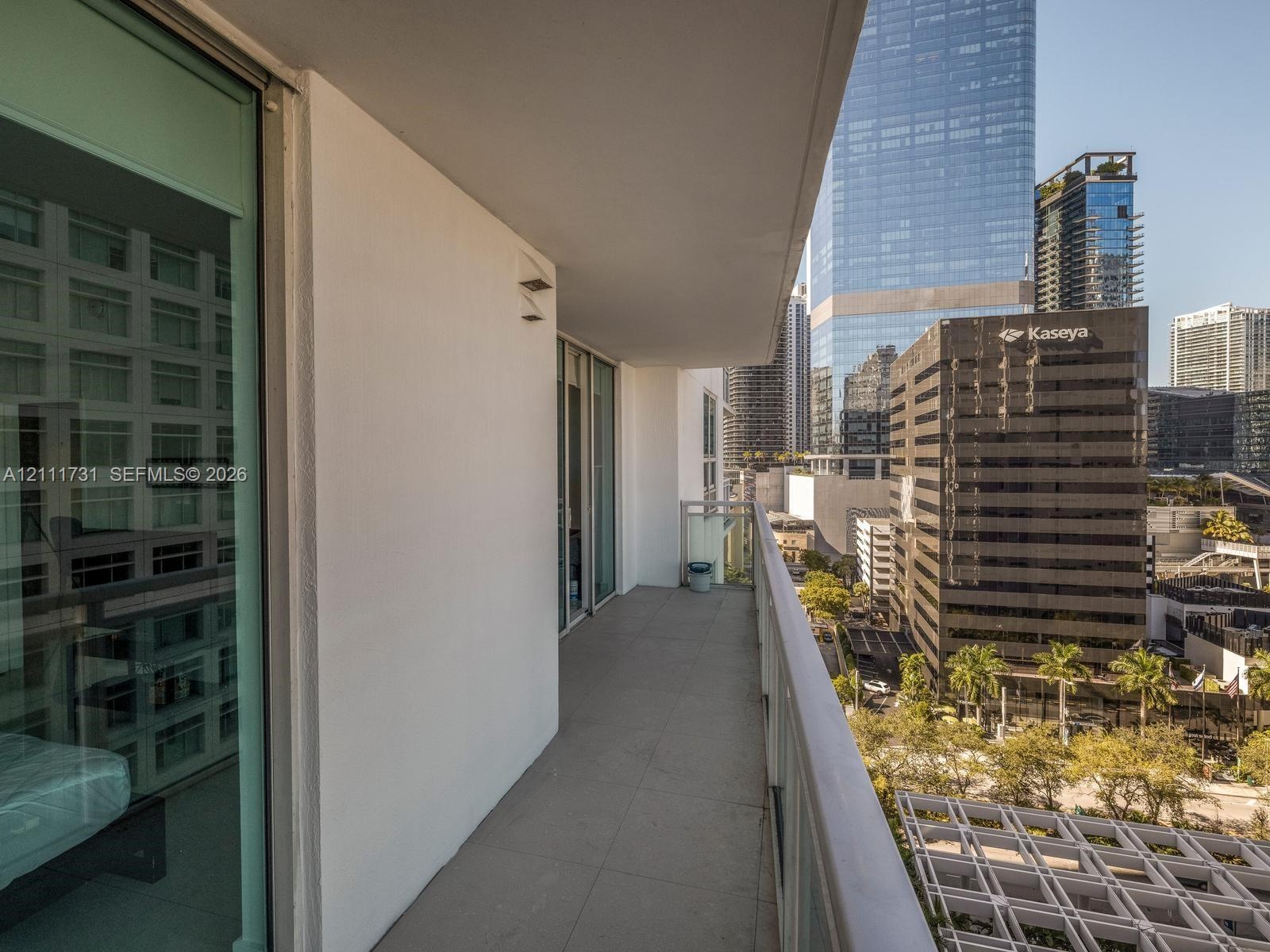 Private balcony featuring concrete flooring, full-height glass panel railings, and access through sliding glass doors