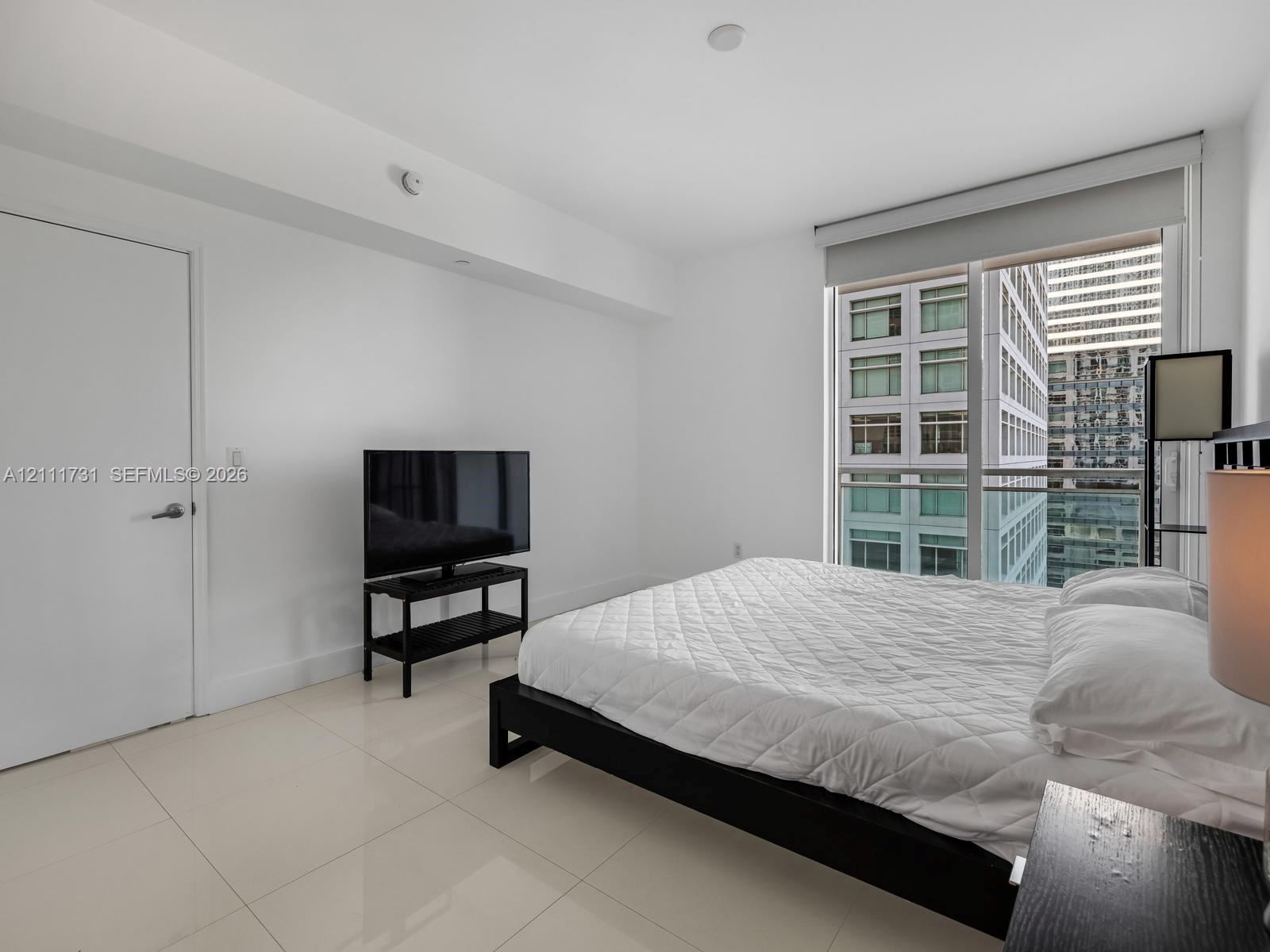 Floor-to-ceiling glass window, large-format tile flooring, neutral wall finish, and solid core interior door
