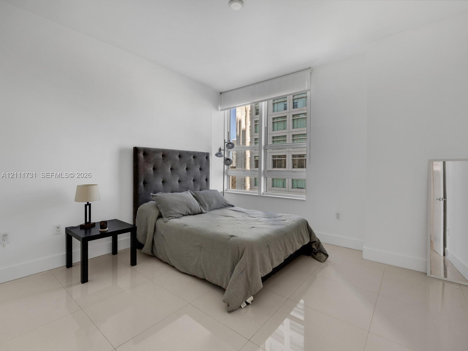 Large-format tile flooring, expansive multi-pane window, and neutral wall palette