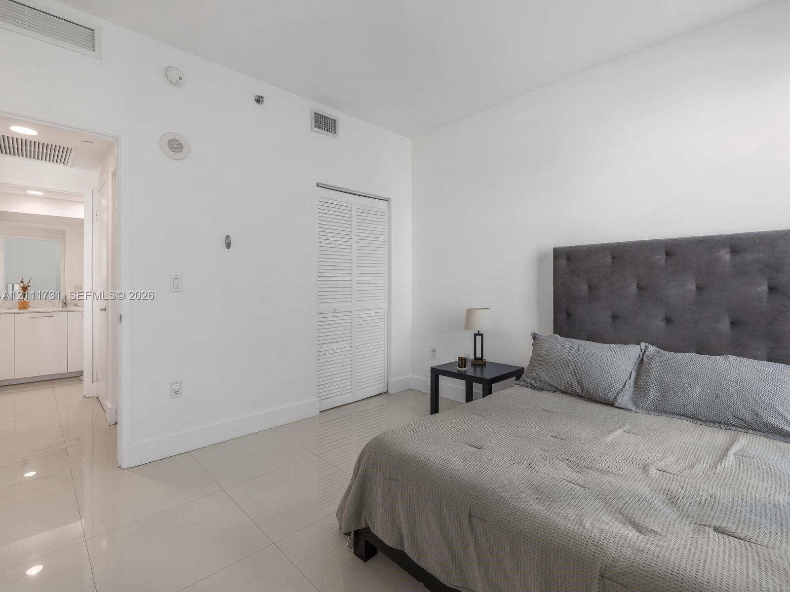 Polished tile flooring, neutral wall finishes, and closet with white louvered doors