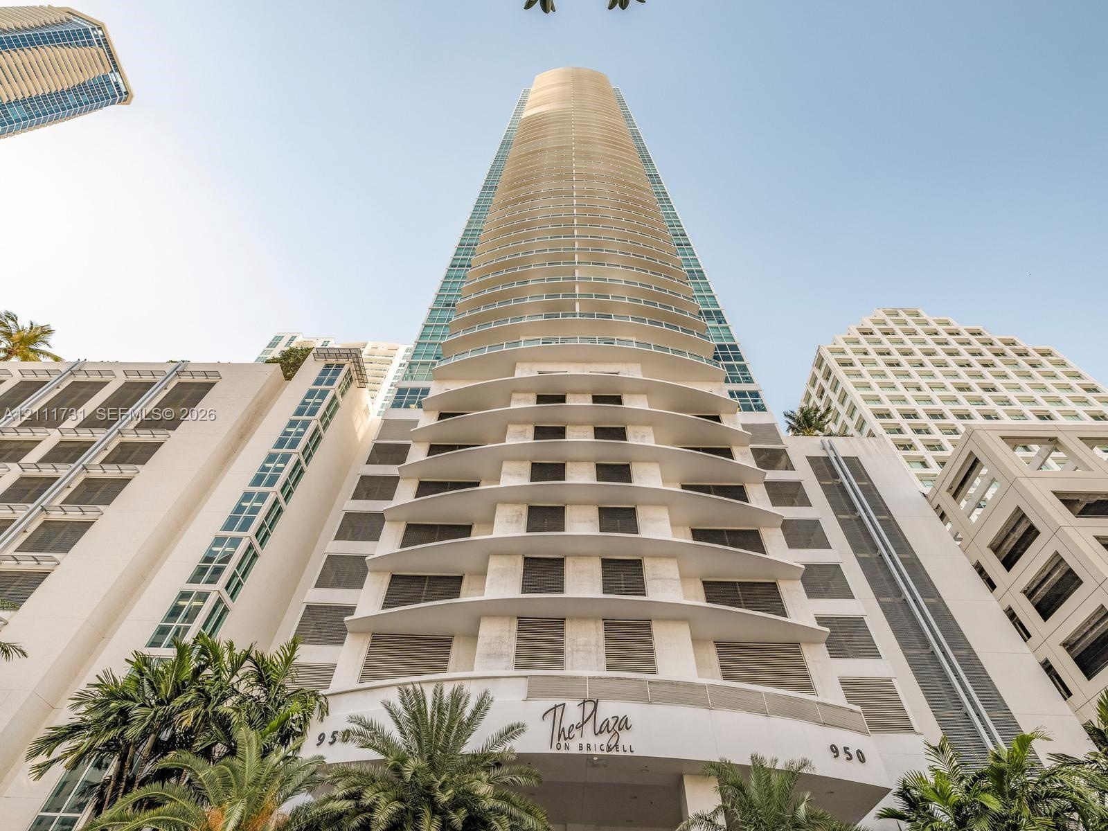 High-rise architectural exterior featuring tiered concrete balconies, glass-paneled facade, and expansive floor-to-ceiling windows