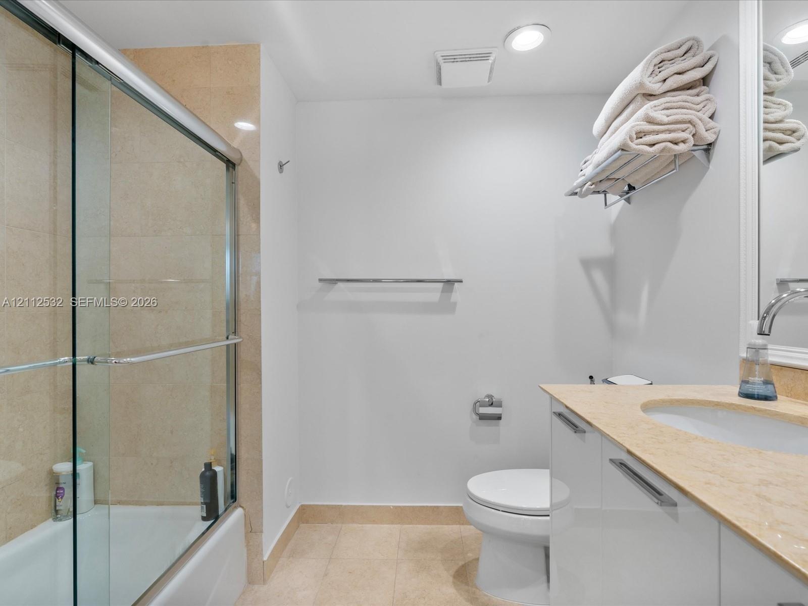 Bathroom featuring a glass-enclosed shower with tiled surround, stone countertop, white vanity cabinetry with chrome hardware, and recessed lighting