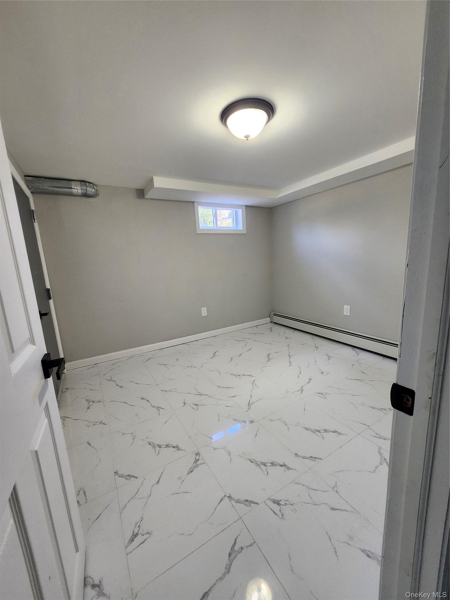 Interior space featuring large-format stone-finish floor tile, neutral wall paint, and a dome-style flush mount ceiling light fixture