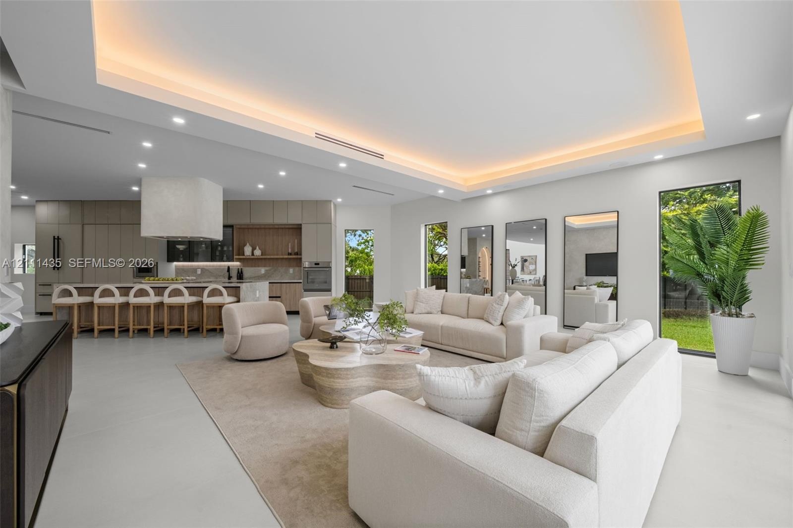 Open-concept interior featuring a recessed tray ceiling with integrated cove lighting, polished concrete flooring, built-in floor-to-ceiling cabinetry