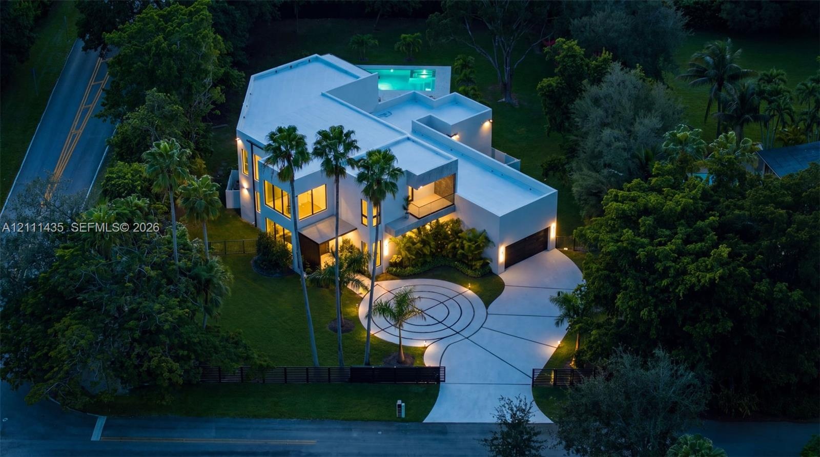 Contemporary multi-level residence featuring a flat roofline, circular decorative concrete driveway, attached multi-car garage, and an elevated swimmi