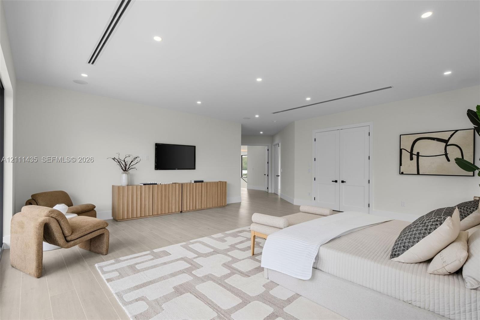Neutral-toned interior featuring wood-finish flooring, recessed LED lighting, integrated linear air vents, and double-panel doors with matte black har