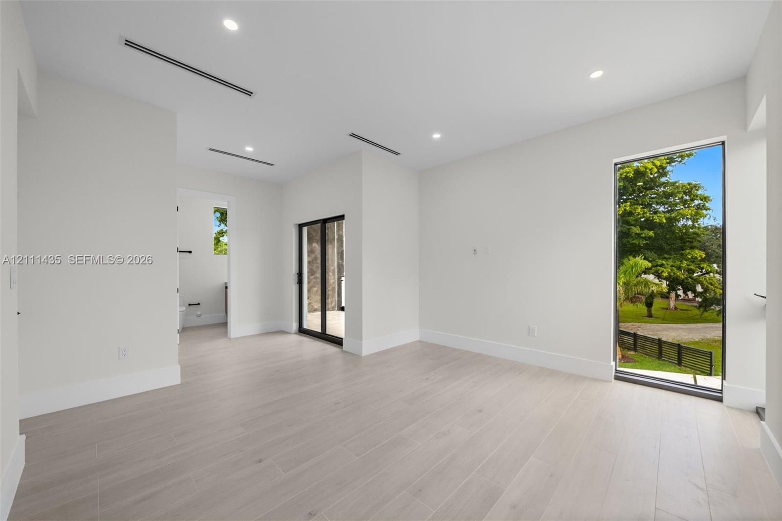Neutral-toned wood-finish flooring, recessed lighting, floor-to-ceiling window, and sliding glass door
