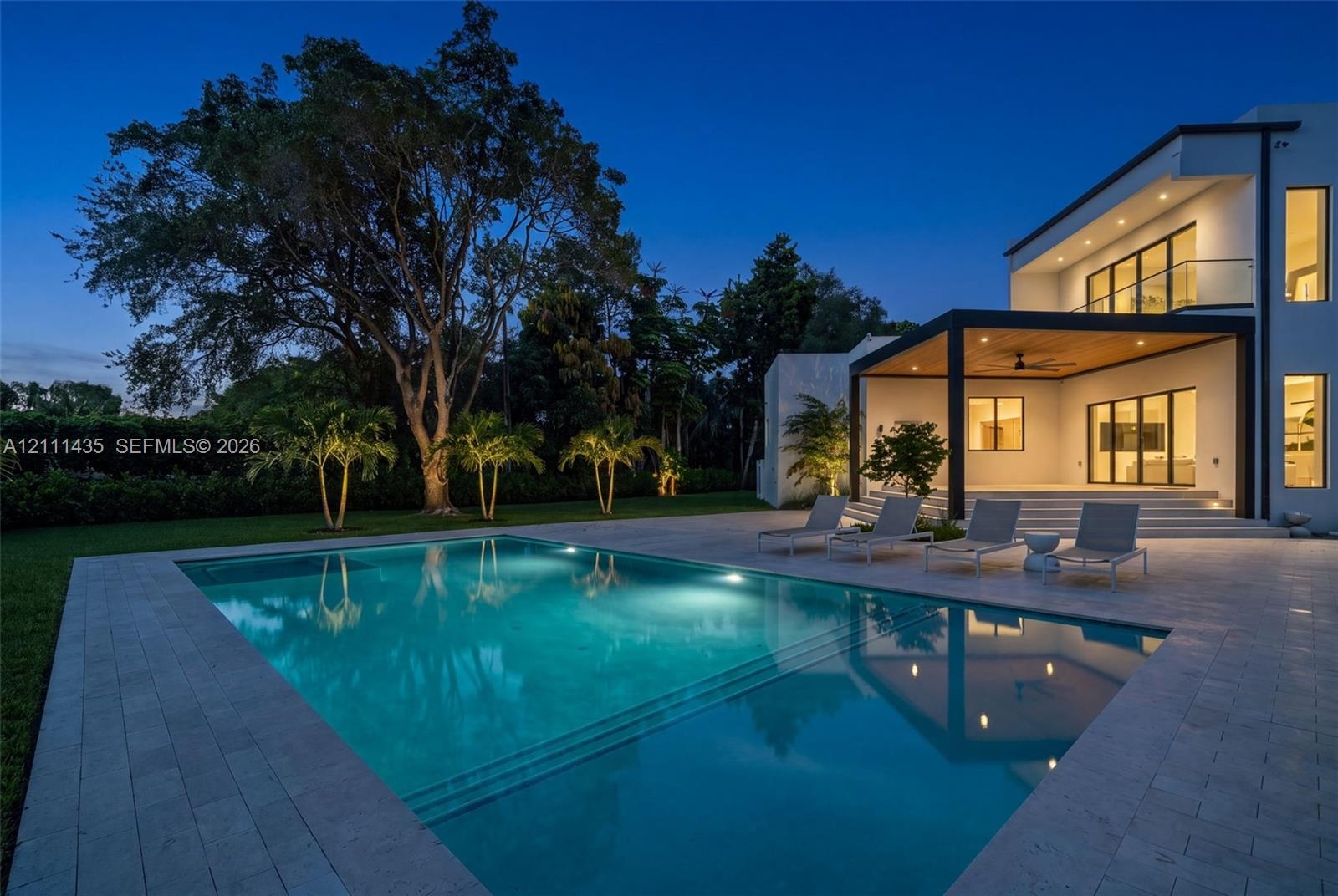 Modern architectural exterior featuring a swimming pool with integrated stairs, expansive stone paver pool deck, covered patio with wood-paneled ceili