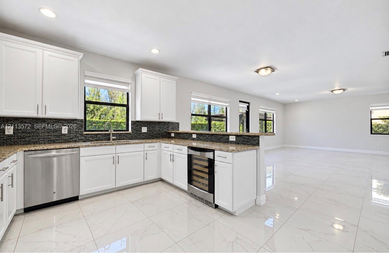 Kitchen featuring white shaker-style cabinetry, stone countertops, a dark-toned tile backsplash, stainless steel appliances, and polished tile floorin