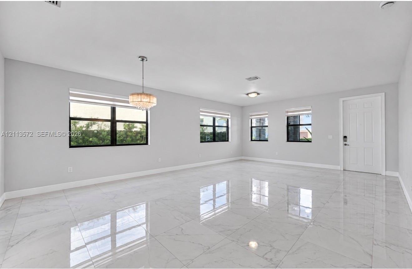 Polished stone-finish flooring, multi-pane windows with black frames, and a tiered crystal chandelier