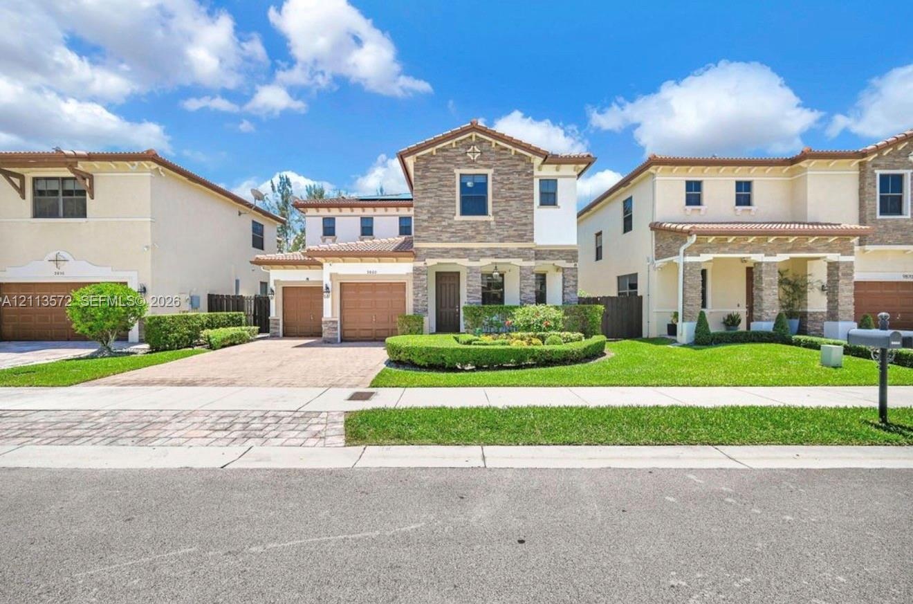Two-story residence featuring a stone-veneer façade, clay tile roof, dual-car garage, and a manicured front lawn