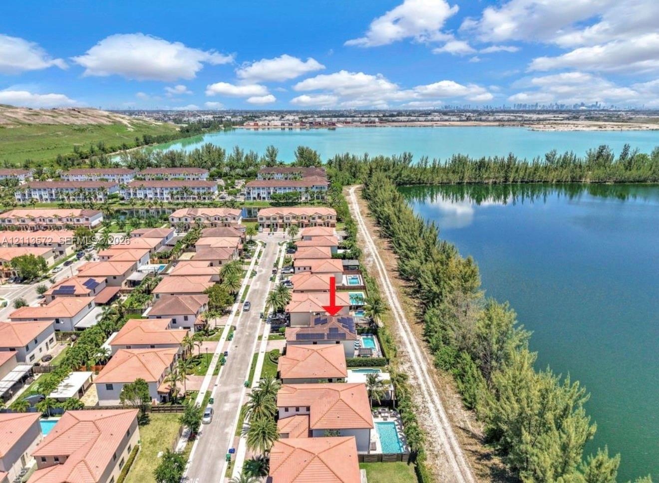 Aerial perspective of a multi-story residence featuring a tile roof, solar panel array, and a private rear swimming pool