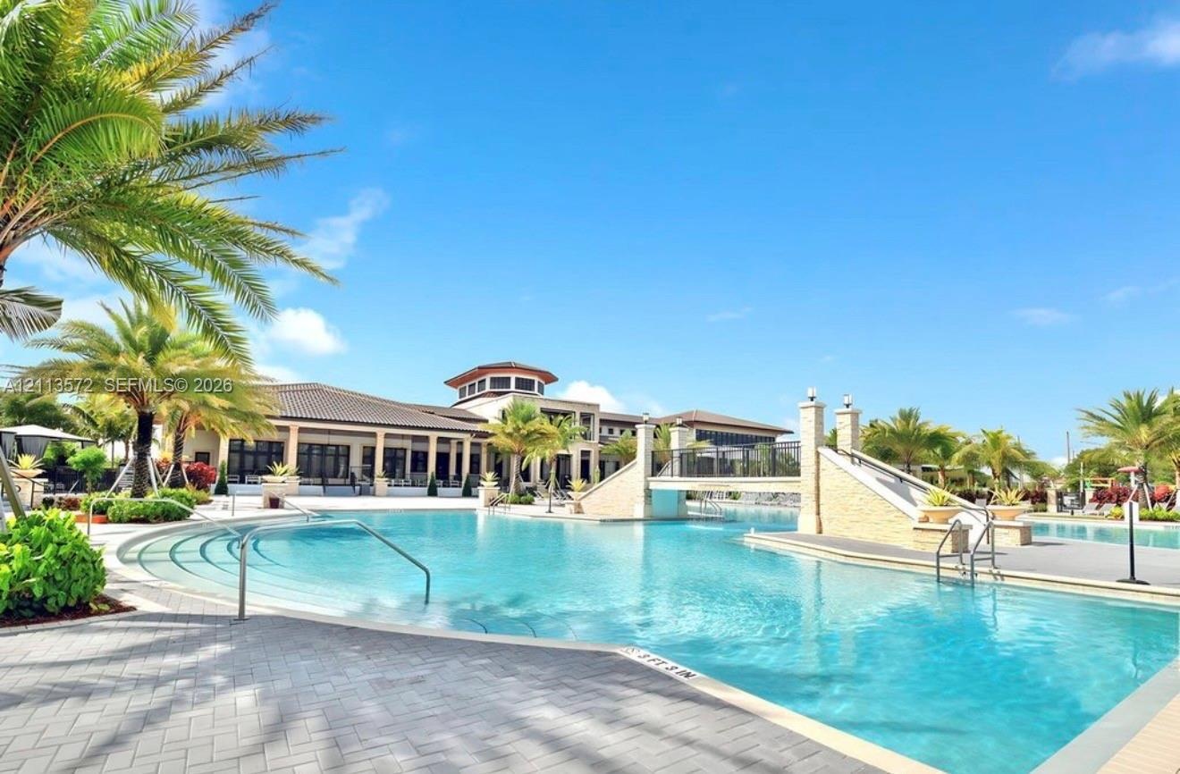 Swimming pool with stone-clad bridge, tiered entry steps, metal handrails, and paver decking